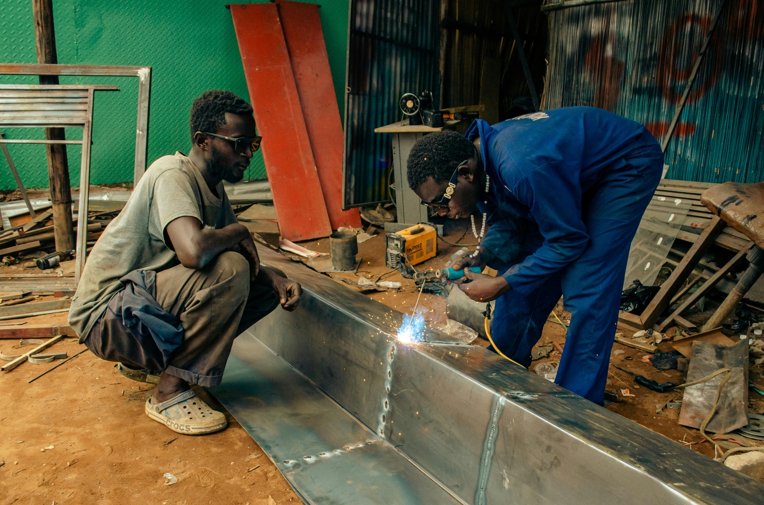 African technicians fabricating stainless steel commercial kitchen equipment in a professional workshop